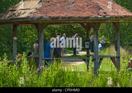 London Wetland Centre, Barnes. Visitors walking around wild area. Rain shelter Pavilion foreground. Wildfowl and Wetlands Trust. Stock Photo