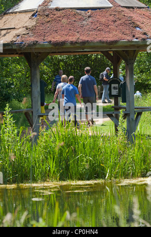 London Wetland Centre, Barnes. Visitors walking around wild area. Rain shelter Pavilion foreground. Wildfowl and Wetlands Trust. Stock Photo