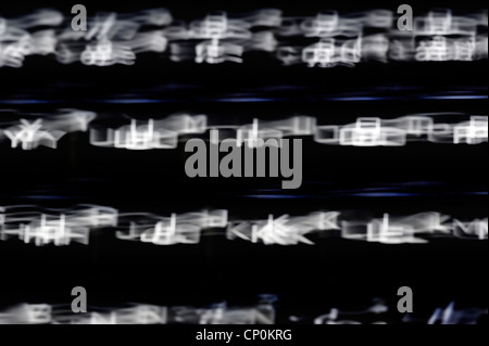 Black computer keyboard with blurry illuminated backlit white letters on keys in the dark Stock Photo