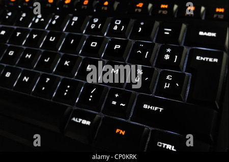 Black computer keyboard with illuminated backlit white characters on keys in the dark Stock Photo