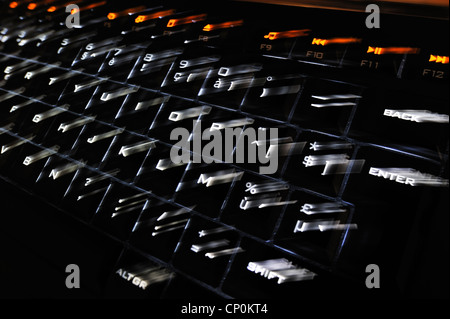 Abstract technology image showing black computer keyboard with illuminated backlit white characters on keys jumping out Stock Photo