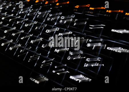 Abstract technology image showing black computer keyboard with illuminated backlit white characters on keys jumping out Stock Photo