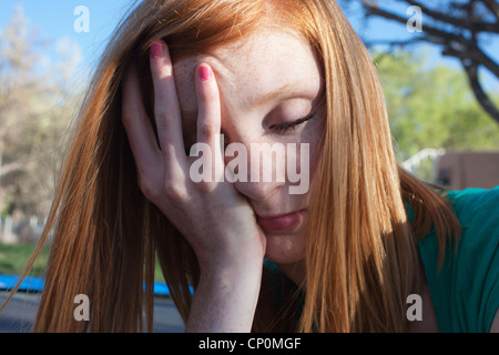 Close up of sixteen year old teen girl with hand on her face.