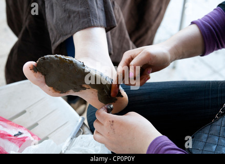 Street artist apply henna on customer's feet. Stock Photo