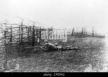 German sniper laying on ground near barbed wire defenses, World War One Stock Photo
