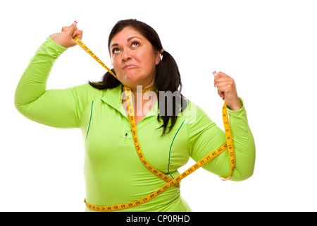 Attractive Frustrated Hispanic Woman Tied Up With Tape Measure Against a White Background. Stock Photo