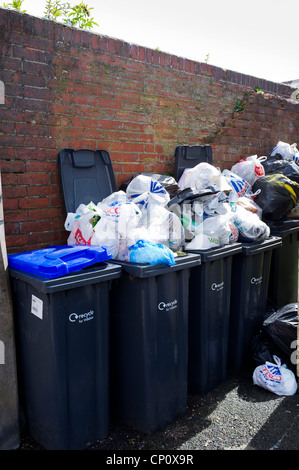 Wheelie bins overflowing with bags of rubbish Stock Photo