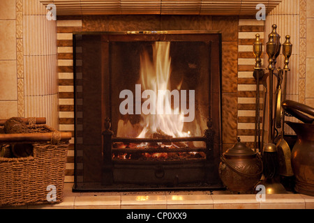 A roaring fire with fireguard, in a domestic house fireplace UK Stock Photo