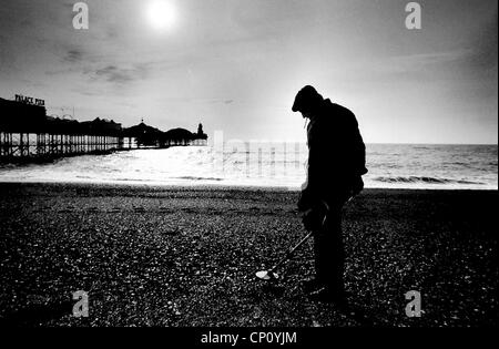 Man silhouetted on Brighton beach using a metal detector by the old Palace Pier UK circa 1984 Stock Photo