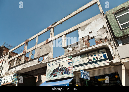 shell of building gutted after 1985 earthquake serves as entrance to public parking lot with small new commercial at sidewalk Stock Photo