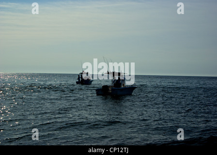 Center console sport fishing boats in silhouette shallow inshore saltwater anchor angling Gulf Mexico Alabama coast Stock Photo