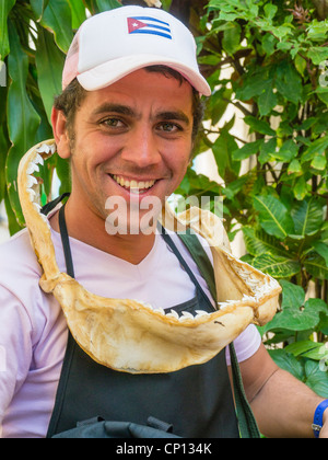 A 20-30 year old Cuban male wears a shark's jaw, with teeth, around his neck like a necklace and smiles in Havana, Cuba. Stock Photo