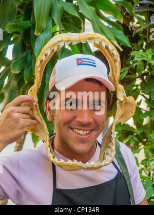 A 20-30 year old Cuban male holds a shark's jaw, with teeth, in front of his face as he makes a funny face in Havana, Cuba. Stock Photo