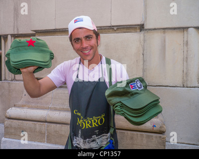 A 20-30 year man holds two types of revolutionary hats with his outstretched arms for sale to tourists in Havana, Cuba. Stock Photo