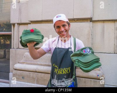 A 20-30 year man holds two types of revolutionary hats with his outstretched arms for sale to tourists in Havana, Cuba. Stock Photo