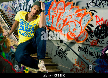 A young african american man rnb music fan posing in front of wall with graffiti with Stock Photo