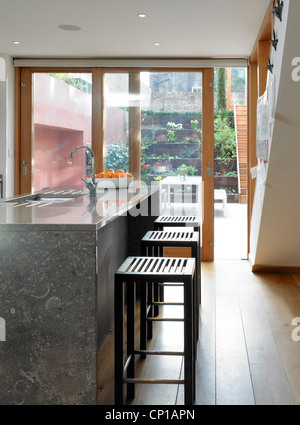 Bar stools at breakfast bar with full-height glass doors to garden, UK. Stock Photo