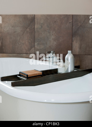 Roll-top bath with wooden bath-rack in pale green bathroom with small white fireplace and voile ...