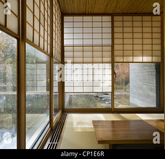 Japanese style sparsely furnished room with sliding screens at the windows Stock Photo