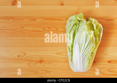 Chinese cabbage head out on a wooden surface. View from the top Stock Photo