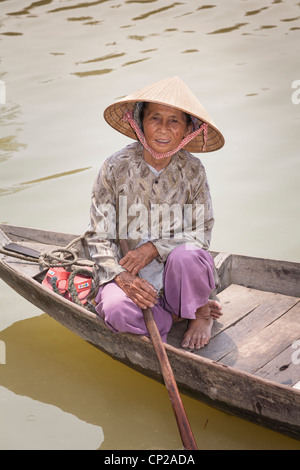 An elderly Vietnamese woman, sitting in a small wooden boat, Hoi An, Quang Nam province, Vietnam Stock Photo