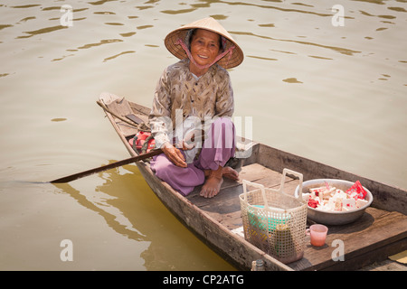 An elderly Vietnamese woman, sitting in a small wooden boat, Hoi An, Quang Nam province, Vietnam Stock Photo