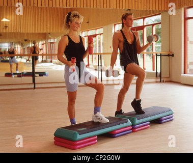 Couple doing steps ith weights in gym, Bracknell, Berkshire, England, United Kingdom Stock Photo