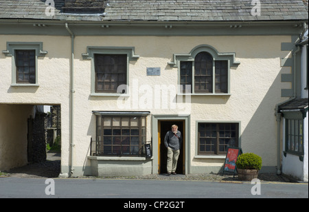 Man coming out the Beatrix Potter Galley, in the village of Hawkshead, Lake District, Cumbria, England UK Stock Photo