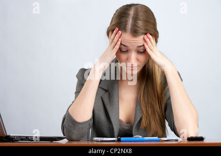 Tired female employee sitting at her desk in office Stock Photo