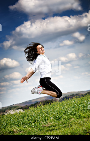 a young jumping woman in front of rural landscape Stock Photo