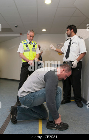 Suspect being searched at charge desk in a police station Stock Photo