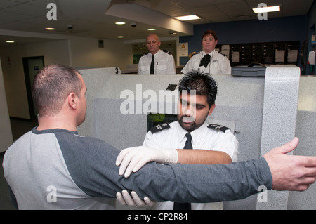 Suspect being searched at charge desk in a police station Stock Photo