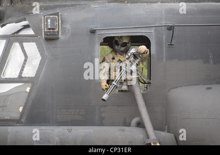 A US Army special operations door gunner wearing a mask to preserve secrecy mans a M134 minigun on a CH-47 Chinook from the 160th Special Operations Aviation Regiment at Simmons Army Airfield April 23, 2012 Fort Bragg, NC. The team is participating in the 2012 U.S. Army Special Operations Command Ca Stock Photo