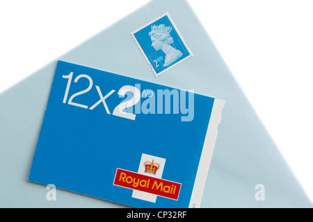 Book of twelve Royal Mail second class postage stamps and an envelope with a stamp isolated on a white background. UK, Britain. Stock Photo