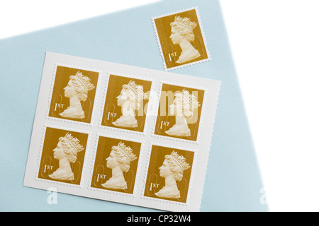 Royal Mail first class postage stamps and an envelope with a stamp on a white. England, UK, Britain. Stock Photo