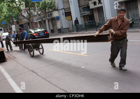 Moving a girder in the street, on wheels, for building construction.  Shanghai, China. Stock Photo