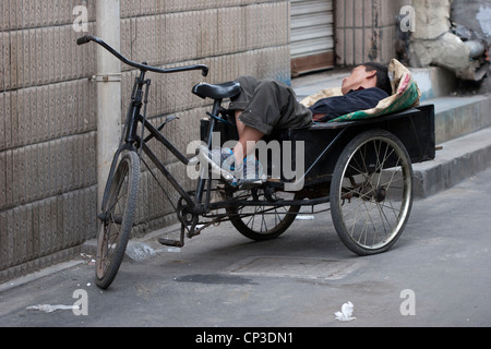 Man asleep on a tricycle rickshaw, Shanghai, China. Stock Photo