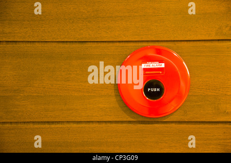 red fire alarm bell set against wood wall Stock Photo