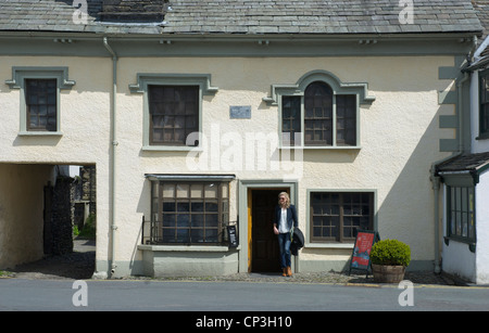 Young Woman standard outside the Beatrix Potter Galley, in the village of Hawkshead, Lake District, Cumbria, England UK Stock Photo