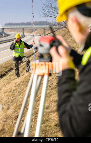 Land surveyors on highway measuring with theodolite Stock Photo