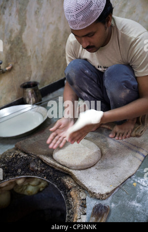L M Rahman kneading and cooking fresh naan bread in the tandoor oven at Karim's Restaurant, Delhi, India Stock Photo