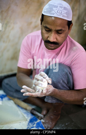 R M Saqir kneading and cooking fresh naan bread in the tandoor oven at Karim's Restaurant, Delhi, India Stock Photo
