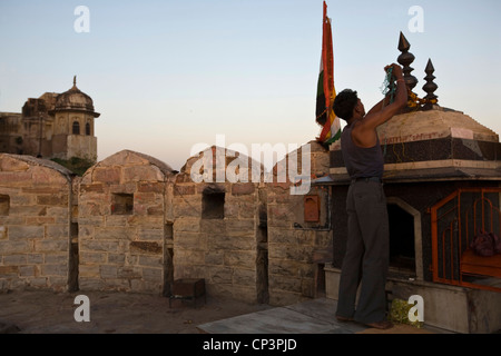 A man decorates a shrine with garlands on the ramparts around the Nahargarh Fort, Jaipur, India Stock Photo