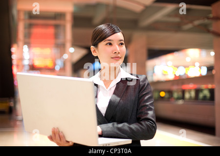 Young businesswoman using her laptop at the train station Stock Photo