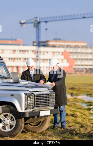 Two architect developers reviewing building plans at construction site Stock Photo