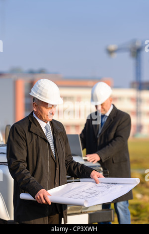 Two architect developers reviewing building plans at construction site Stock Photo