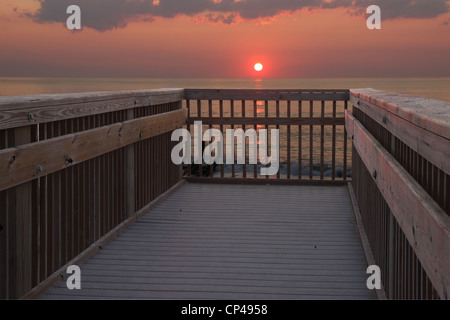 The sun is just above the horizon over the Atlantic ocean in early morning at a public beach access in Nags Head, North Carolina Stock Photo