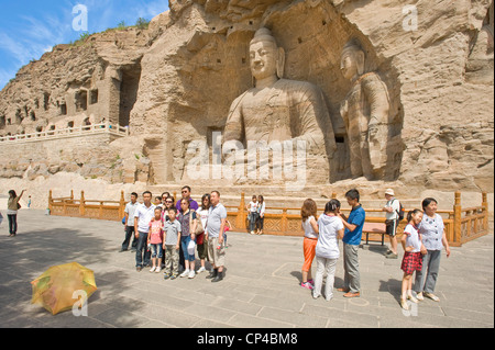 Tourists pose for the camera at the Ratnasambhava Bodhisattva Cave (Cave 19) at the Yungang Grottoes - 2nd tallest at 16.8 mtrs. Stock Photo