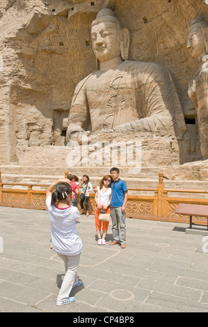 Tourists pose for the camera at the Ratnasambhava Bodhisattva Cave (Cave 19) at the Yungang Grottoes - 2nd tallest at 16.8 mtrs. Stock Photo