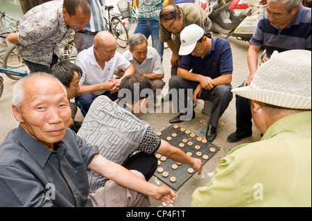 Local people playing Xiangqi (Chinese Chess) on the street while onlookers watch the game. Stock Photo